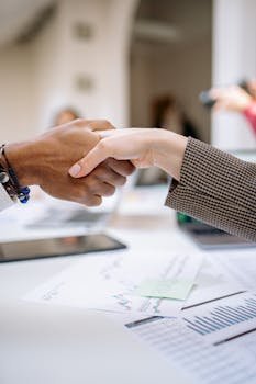 Close-up of a professional handshake over business documents, symbolizing partnership and agreement.